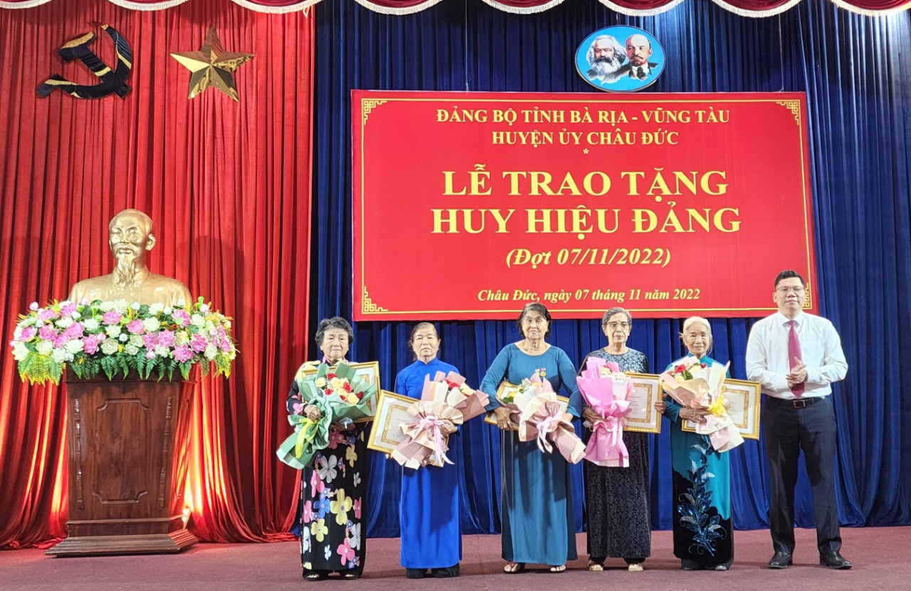 Ông Hoàng Nguyên Dinh, Bí thư Huyện uỷ trao Huy hiệu 55 tuổi Đảng và tặng hoa chúc mừng các đảng viên.