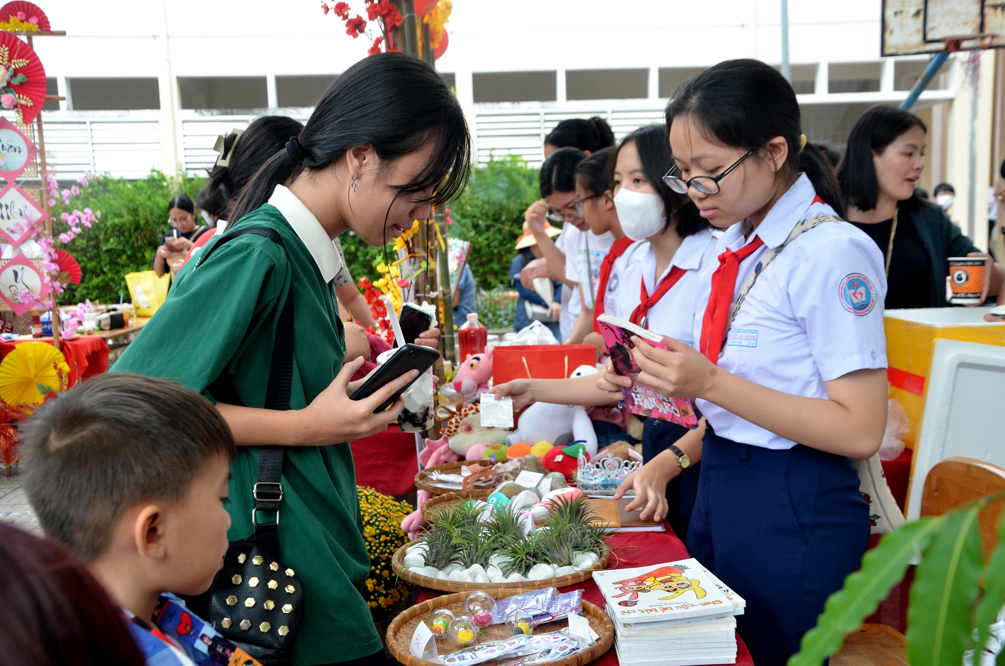 Các gian hàng của các lớp luôn đông khách. Trong ảnh: HS mua sản phẩm vẽ trên đá của HS lớp 9.4 tại phiên chợ.