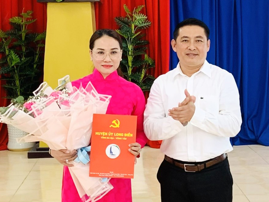 Ông Huỳnh Sơn Tuấn, Bí thư Huyện ủy Long Điền trao quyết định và tặng hoa chúc mừng cho bà Nguyễn Thị Mỹ Lệ.