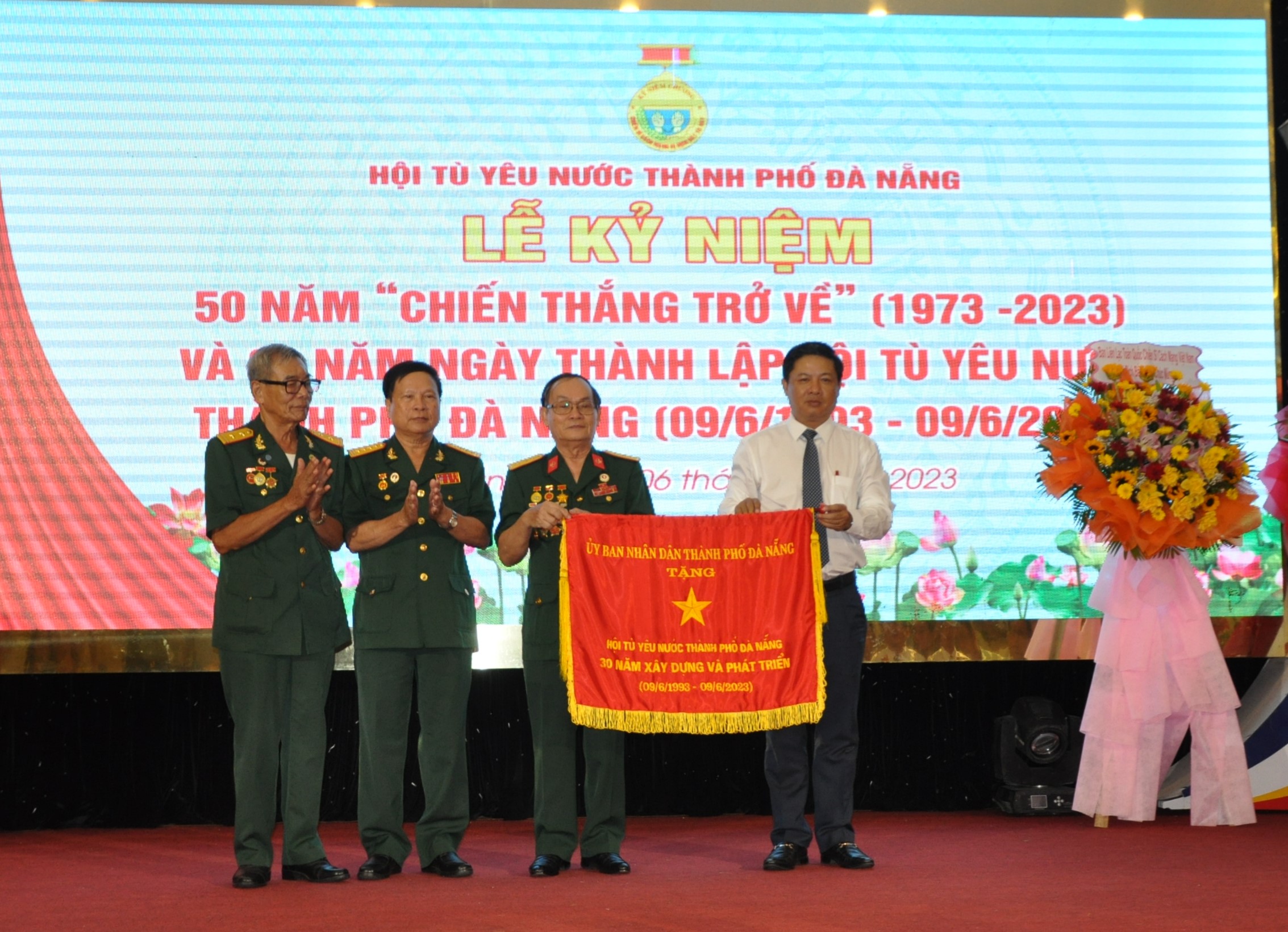 Cựu tù Côn Đảo Thân Vĩnh Vân (thứ 3 từ trái sang) thay mặt Hội Tù yêu nước nhận cờ  của UBND TP.Đà Nẵng trao tặng.