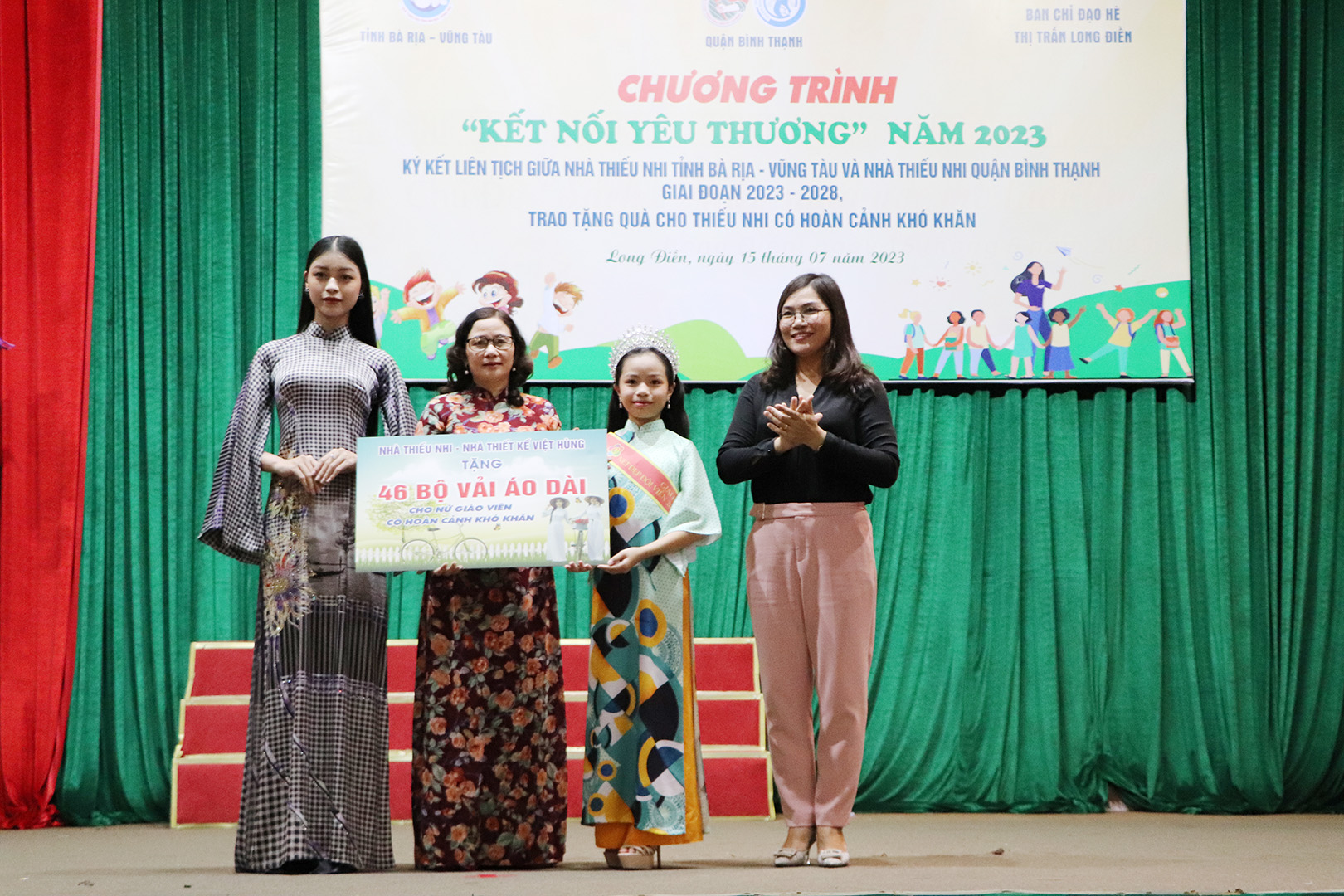 Đại diện Nhà thiếu nhi tặng bảng tượng trưng 46 bộ vải áo dài đến GV các trường tiểu học huyện Long Điền.