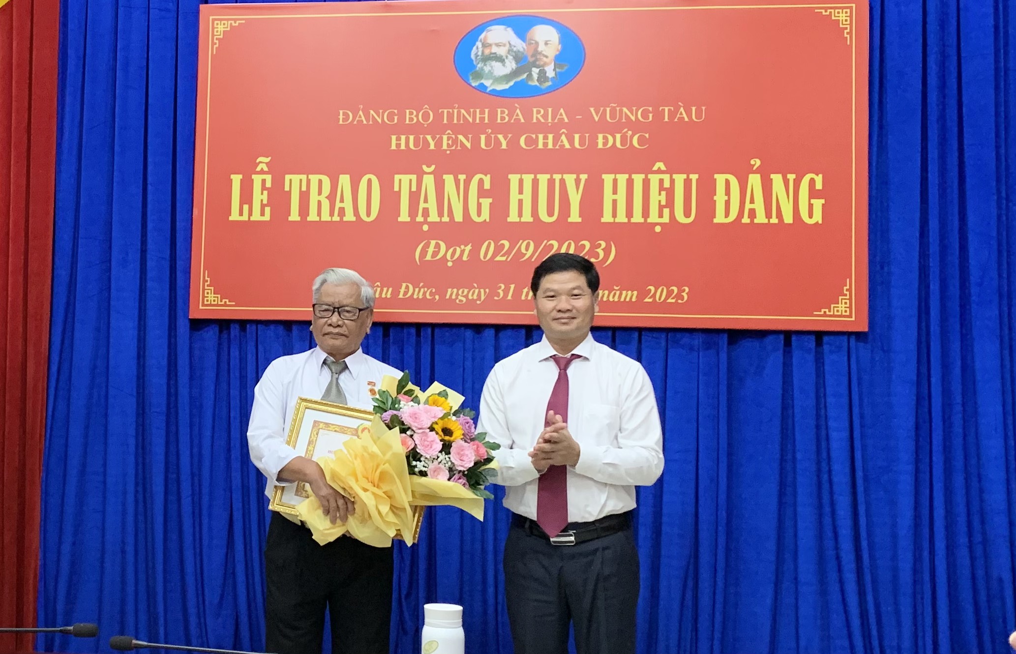 Ông Lê Thanh Liêm, Phó Bí thư Thường trực Huyện ủy Châu Đức trao Huy hiệu 60 năm tuổi Đảng cho đảng viên Phạm Bá Tiềm (82 tuổi, Đảng bộ xã Bàu Chinh). 