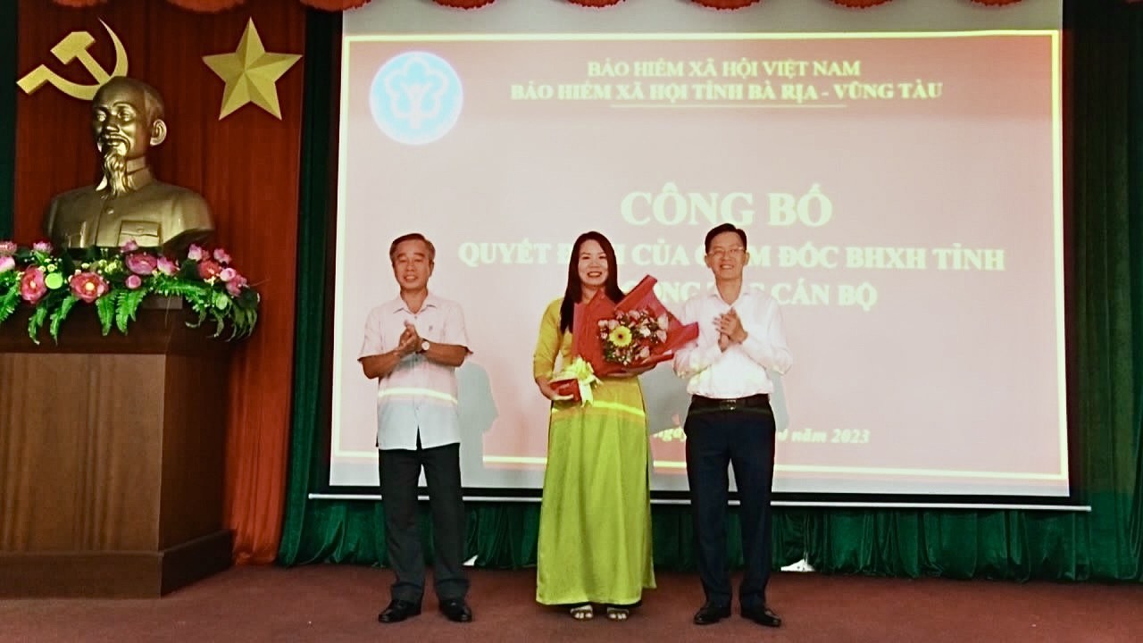 Ông Phạm Ngọc Sơn, Bí thư Đảng ủy, Giám đốc BHXH tỉnh (bên phải) và ông Võ Hữu Hạnh, Phó Bí thư thường trực Huyện ủy Long Điền trao quyết định và tặng hoa chúc mừng bà Hoàng Việt Hà, tân Giám đốc BHXH huyện Long Điền.