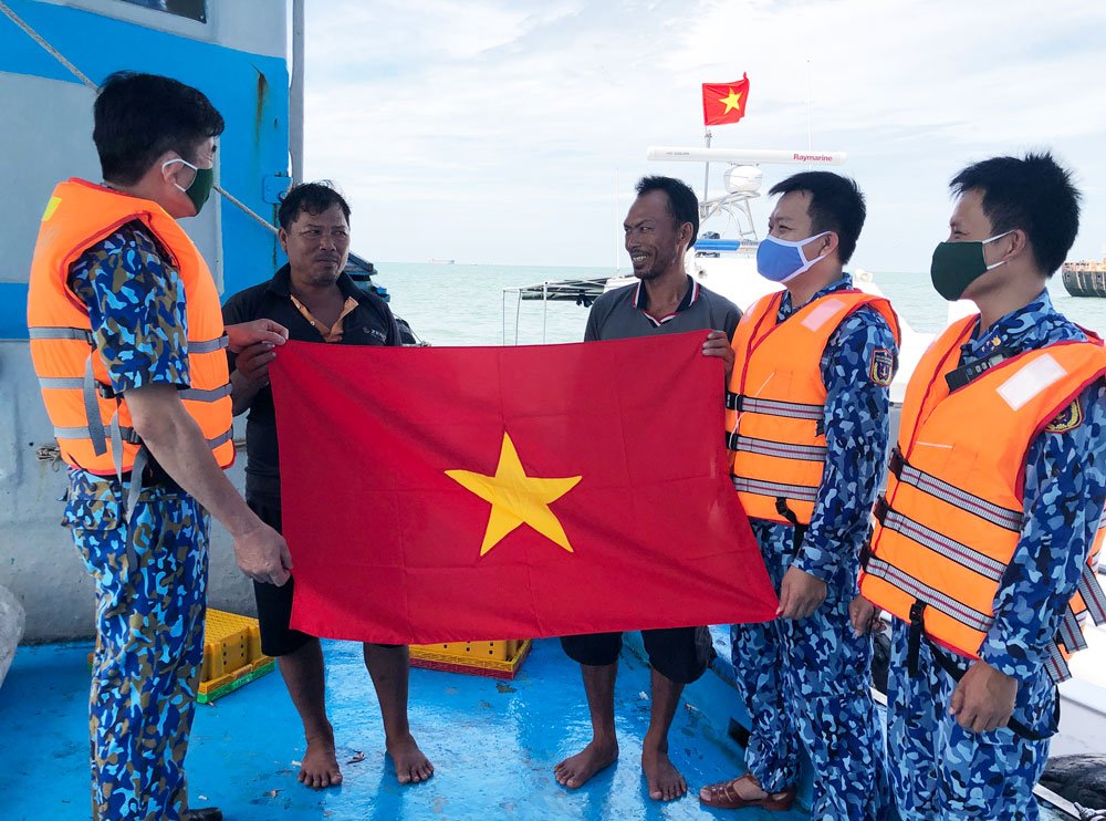 Cán bộ, chiến sĩ Vùng Cảnh sát biển 3 tuyên truyền biển, đảo và tặng cờ Tổ quốc cho ngư dân. Ảnh: NHÂN ĐOÀN