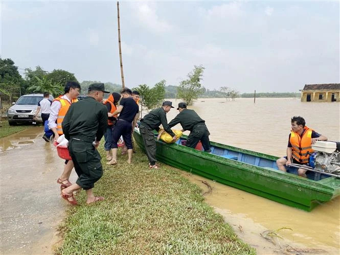 Cán bộ, chiến sỹ của thuộc Tiểu đoàn 2, Trung đoàn Cảnh sát Cơ động Bắc Trung Bộ vận chuyển lương thực, thực phẩm lên thuyền để chuyển vào vùng ngập, đầu tháng 11/2023. (Ảnh: Hữu Quyết/TTXVN)