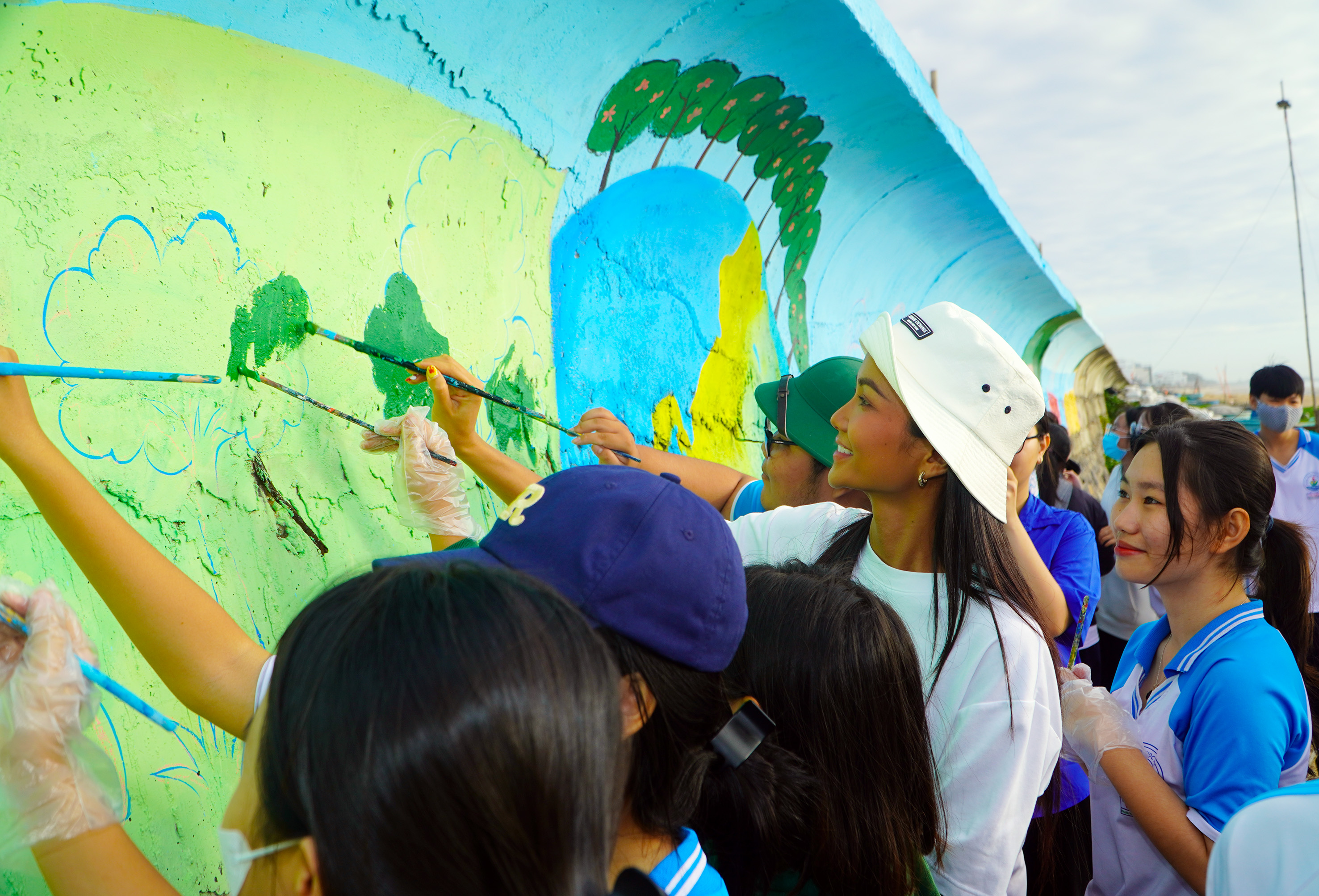 Hoa hậu H'Hen Niê và các em HS, SV cùng vẽ tranh bích họa lên bờ kè bãi biển Phước Hải.