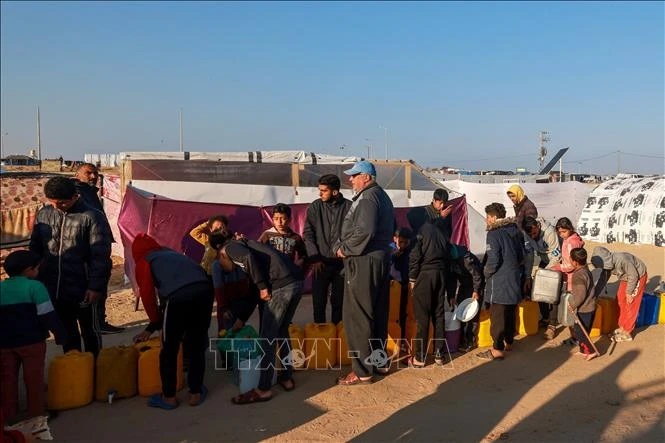 Người tị nạn Palestine xếp hàng lấy nước sinh hoạt tại khu lều tạm ở Dải Gaza ngày 16/1/2024.