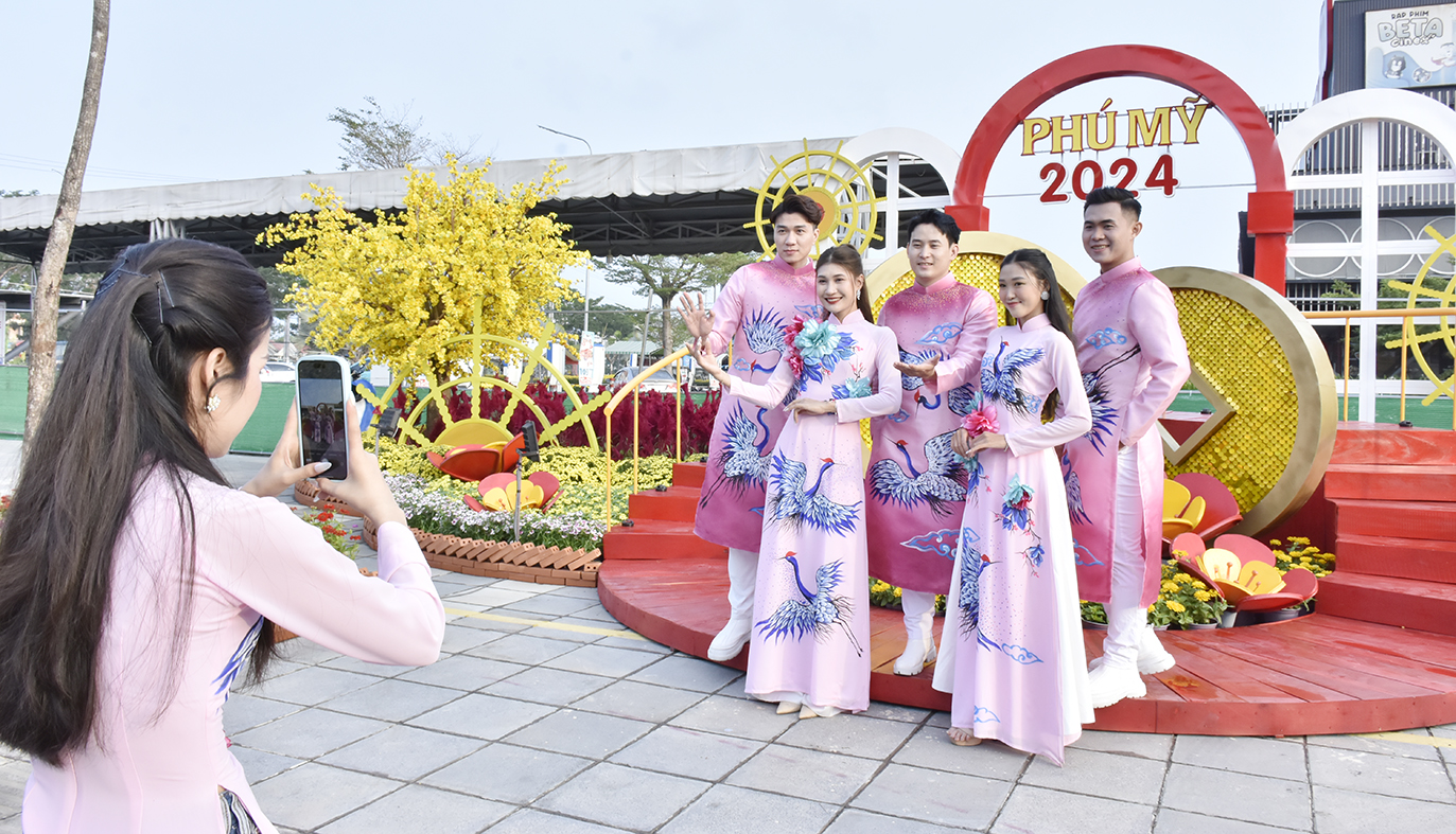 Một nhóm bạn trẻ xúng xính áo dài check in đường hoa Phú Mỹ trong buổi sáng khai mạc