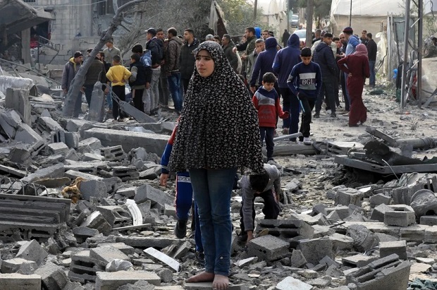 Người dân Palestine bên đống đổ nát của những tòa nhà bị phá hủy sau các cuộc không kích của Israel tại thành phố Rafah, Dải Gaza.