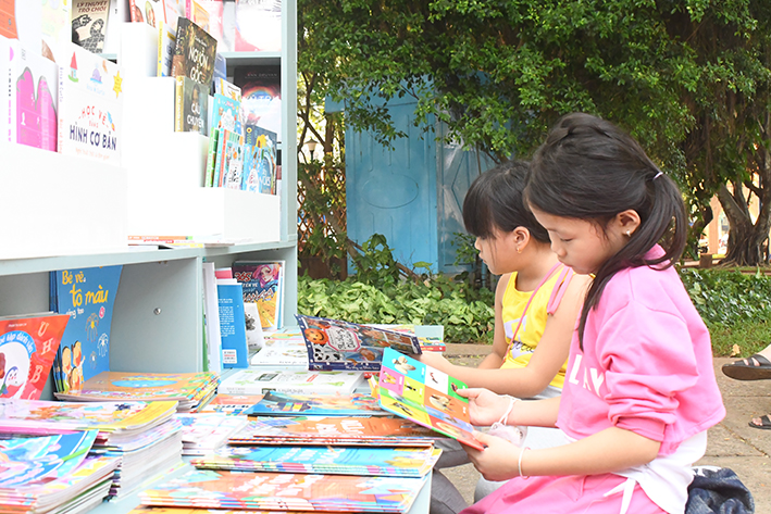 Trẻ đọc sách tại quầy sách di động của ông Hoàng Phúc Cương tại Công viên Bãi Trước, TP.Vũng Tàu.