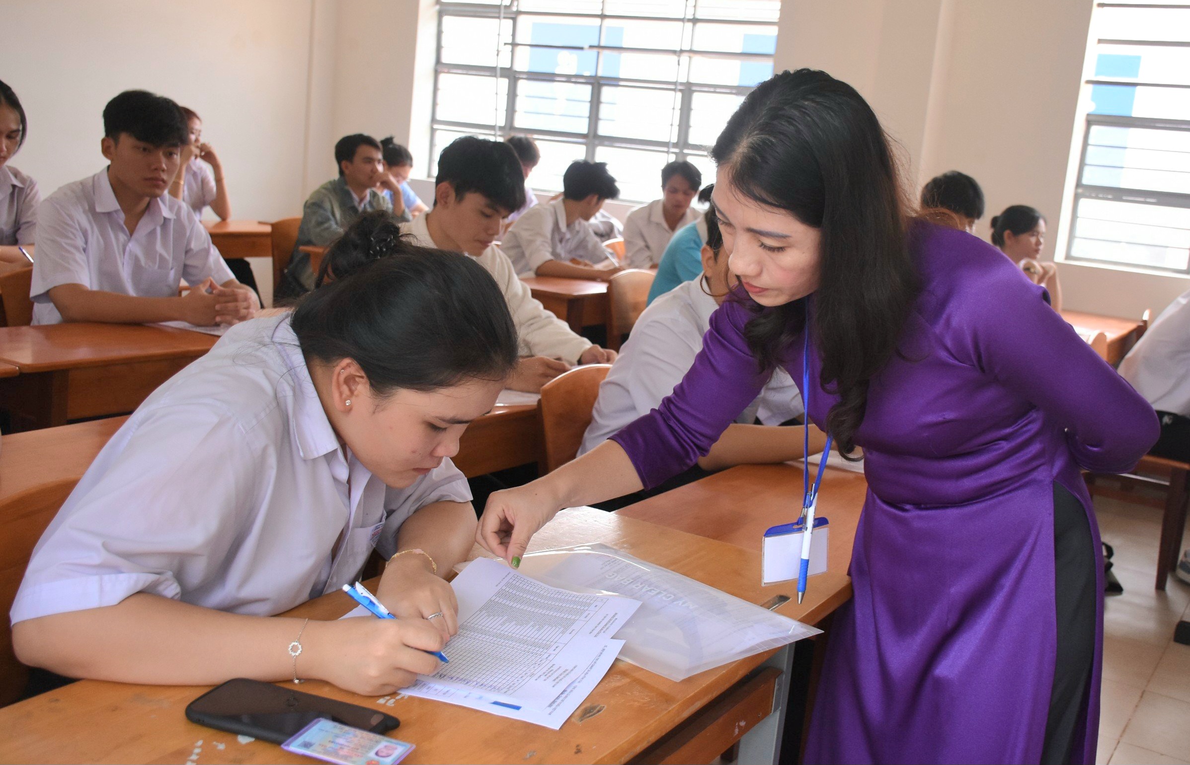 Cán bộ coi thi điểm thi THPT Nguyễn Trãi (huyện Châu Đức) cho thí sinh đối chiếu thông tin và ký xác nhận. Ảnh: NGỌC BÍCH