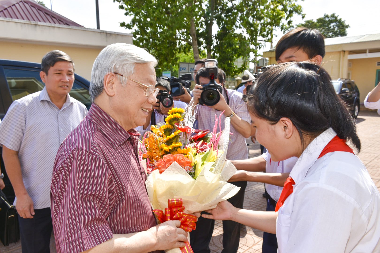 Tổng Bí thư Nguyễn Phú Trọng đón nhận bó hoa tươi thắm từ hai em Bùi Thị Yến Vy và Nguyễn Hữu Tú. Ảnh: NGỌC NGUYỄN.