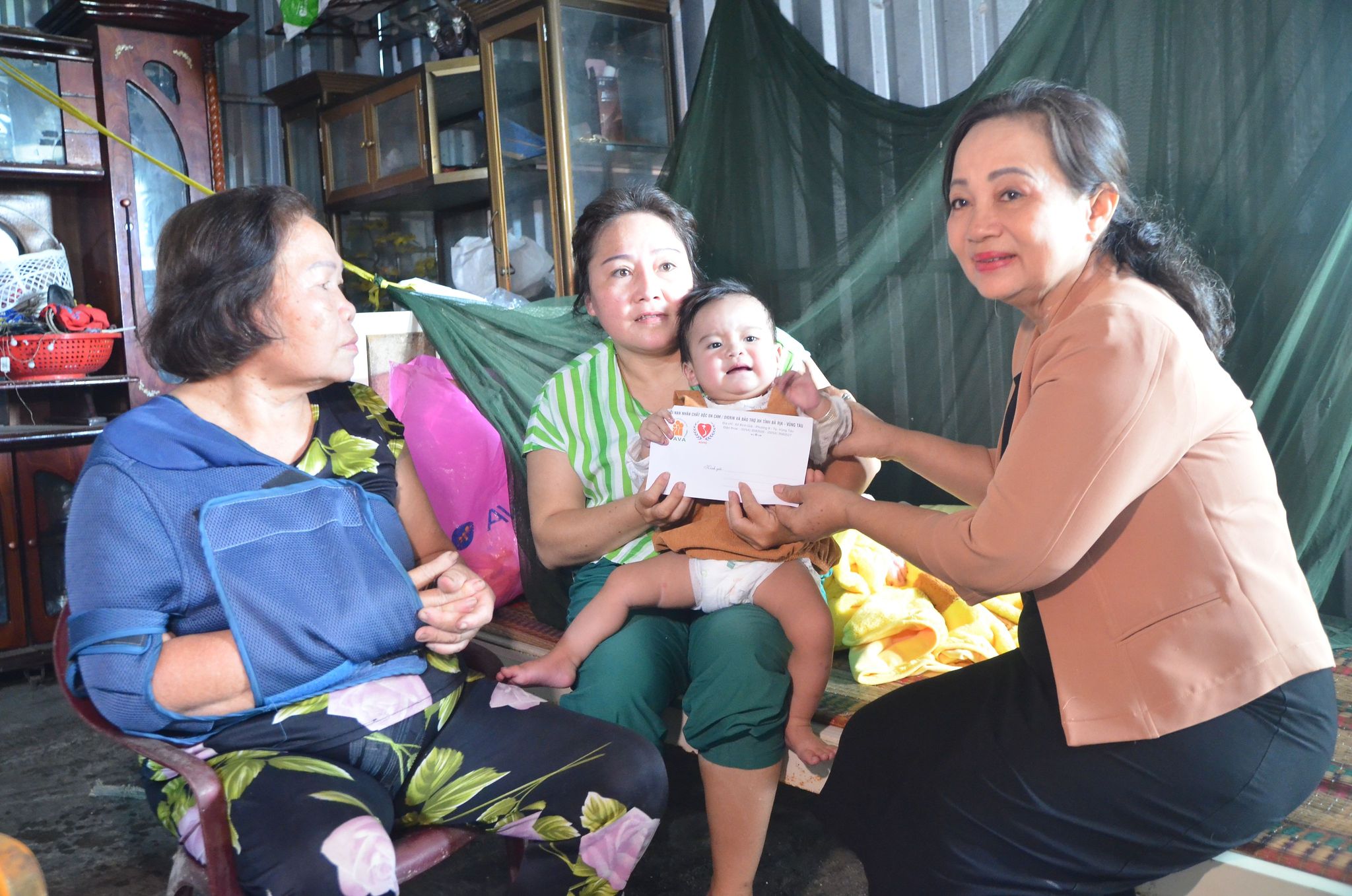 Bà Trương Thị Hường, Phó Chủ tịch Hội Nạn nhân chất độc da cam/Dioxin và Bảo trợ xã hội tỉnh tặng quà cho bé Nguyễn Kim Ngân, 10 tháng tuổi, vừa được Hội hỗ trợ chi phí mổ bệnh tim bẩm sinh.