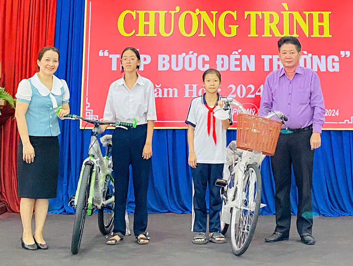 Ông Lê Văn Khương, Phó Chủ tịch UBND phường Phú Mỹ cùng nhà hảo tâm tặng xe đạp cho các em HS nghèo vượt khó. Ảnh: MINH QUANG