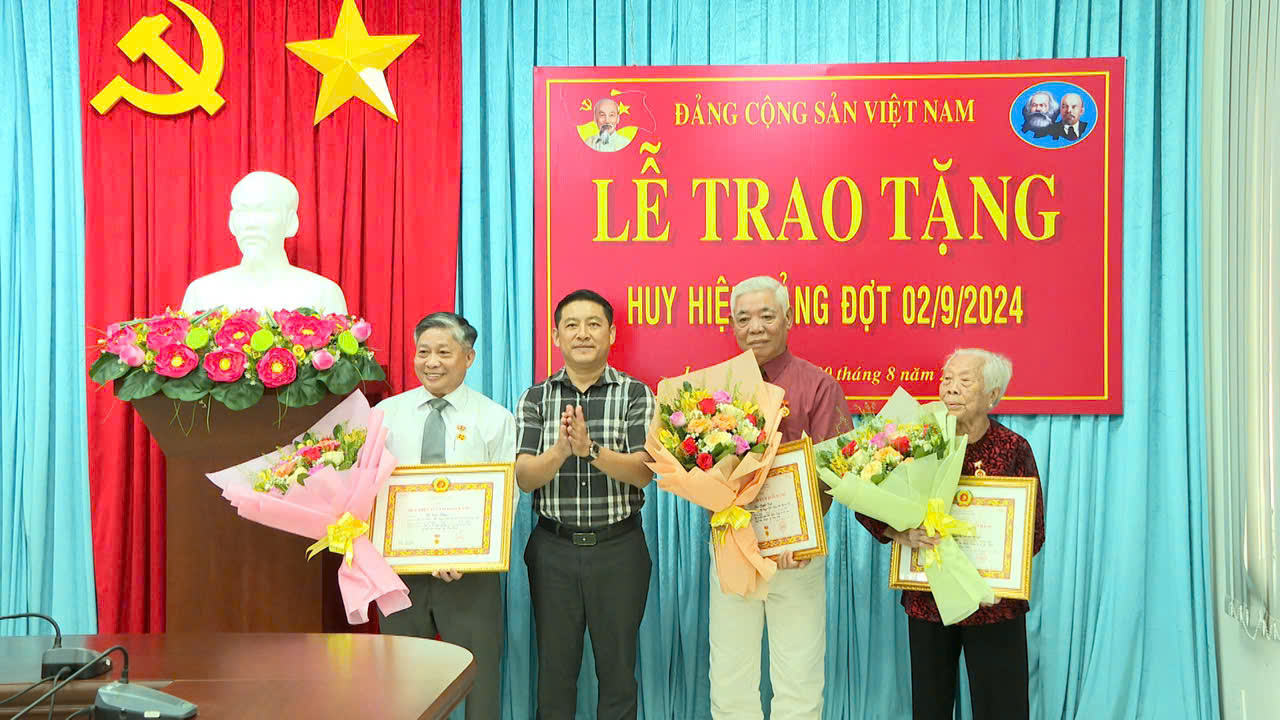 Ông Huỳnh Sơn Tuấn, Bí thư Huyện ủy Long Điền trao Huy hiệu đảng và tặng hoa chúc mừng cho các đảng viên.