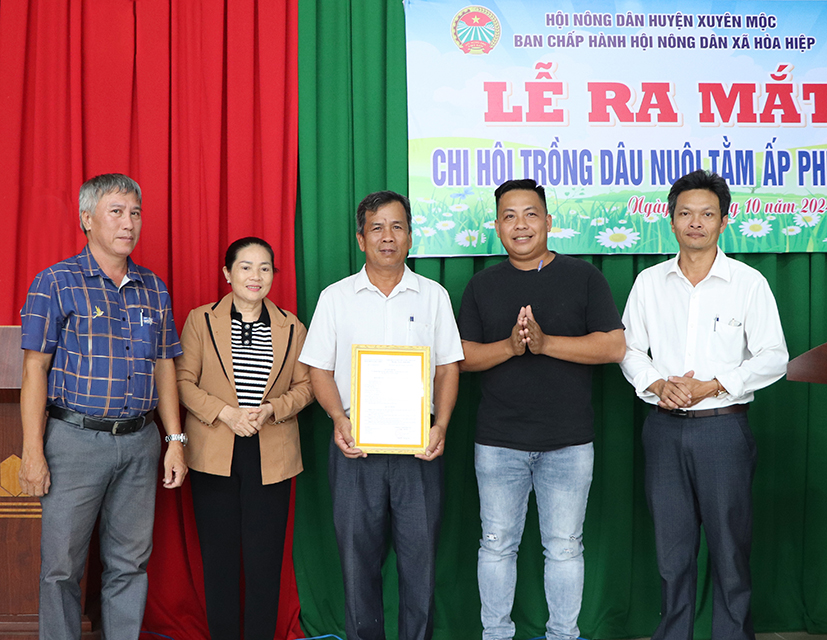 Ông Dương Tấn Linh (bên phải), Chủ tịch Hội Nông dân huyện Xuyên Mộc; ông Phan Tấn Diện (bên trái), Phó Bí thư Thường trực Đảng ủy xã Hòa Hiệp trao Quyết định thành lập và tặng hoa chúc mừng Chi hội nghề nghiệp trồng dâu nuôi tằm tại lễ ra mắt.