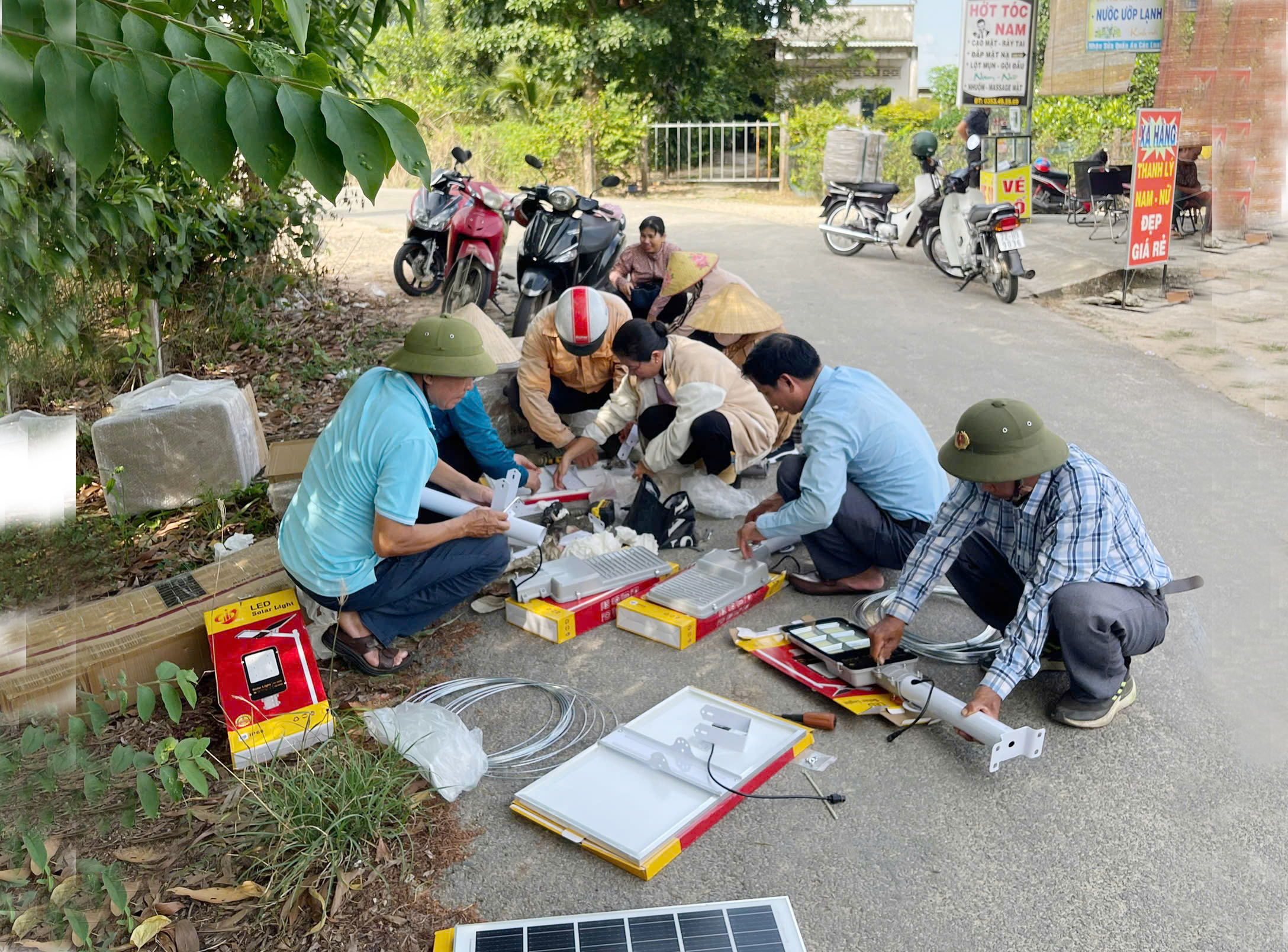 Cán bộ, đảng viên và người dân chuẩn bị đèn để lắp đặt tại tuyến đường.