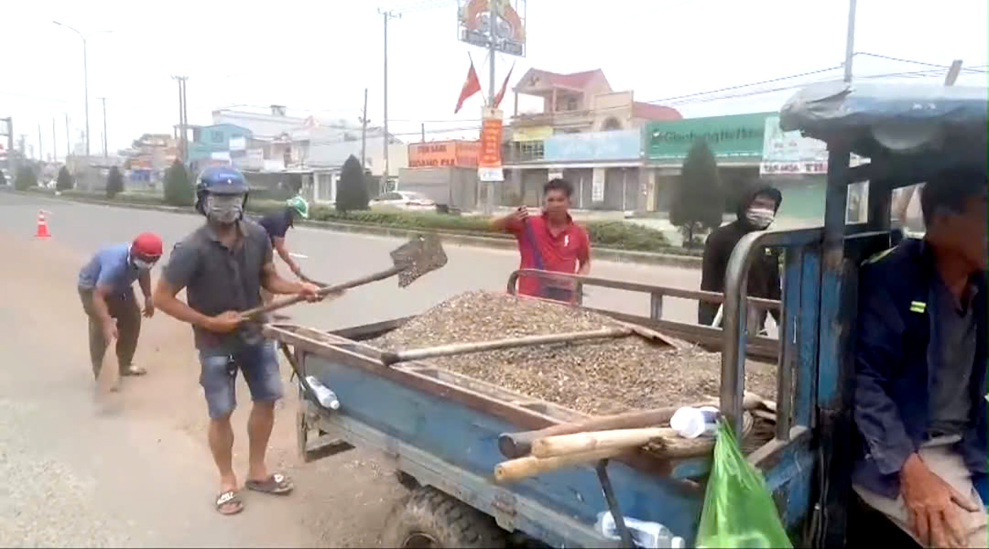 Tài xế thuê người thu gom vật liệu rơi vãi xuống đường.