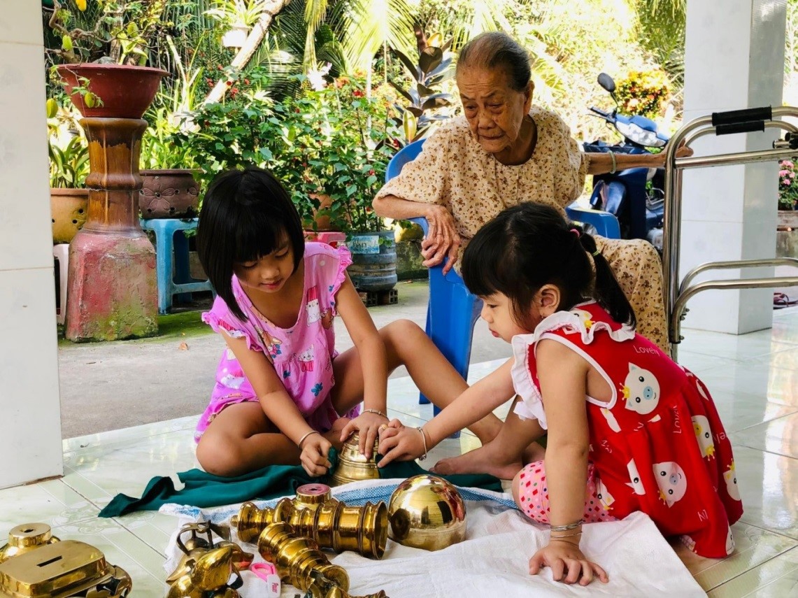 Ngoại hướng dẫn cháu đánh bóng lư đồng đón Tết.