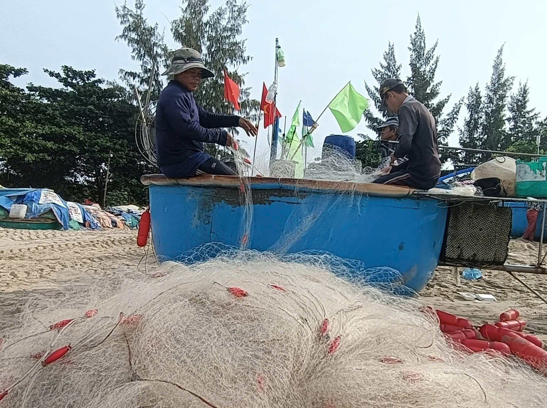 Hai cha con ngư dân thu lưới sau khi bán cá cho thương lái, chuẩn bì sẵn sàng cho ngày mai tiếp tục ra khơi một ngày nữa mới nghỉ Tết.
