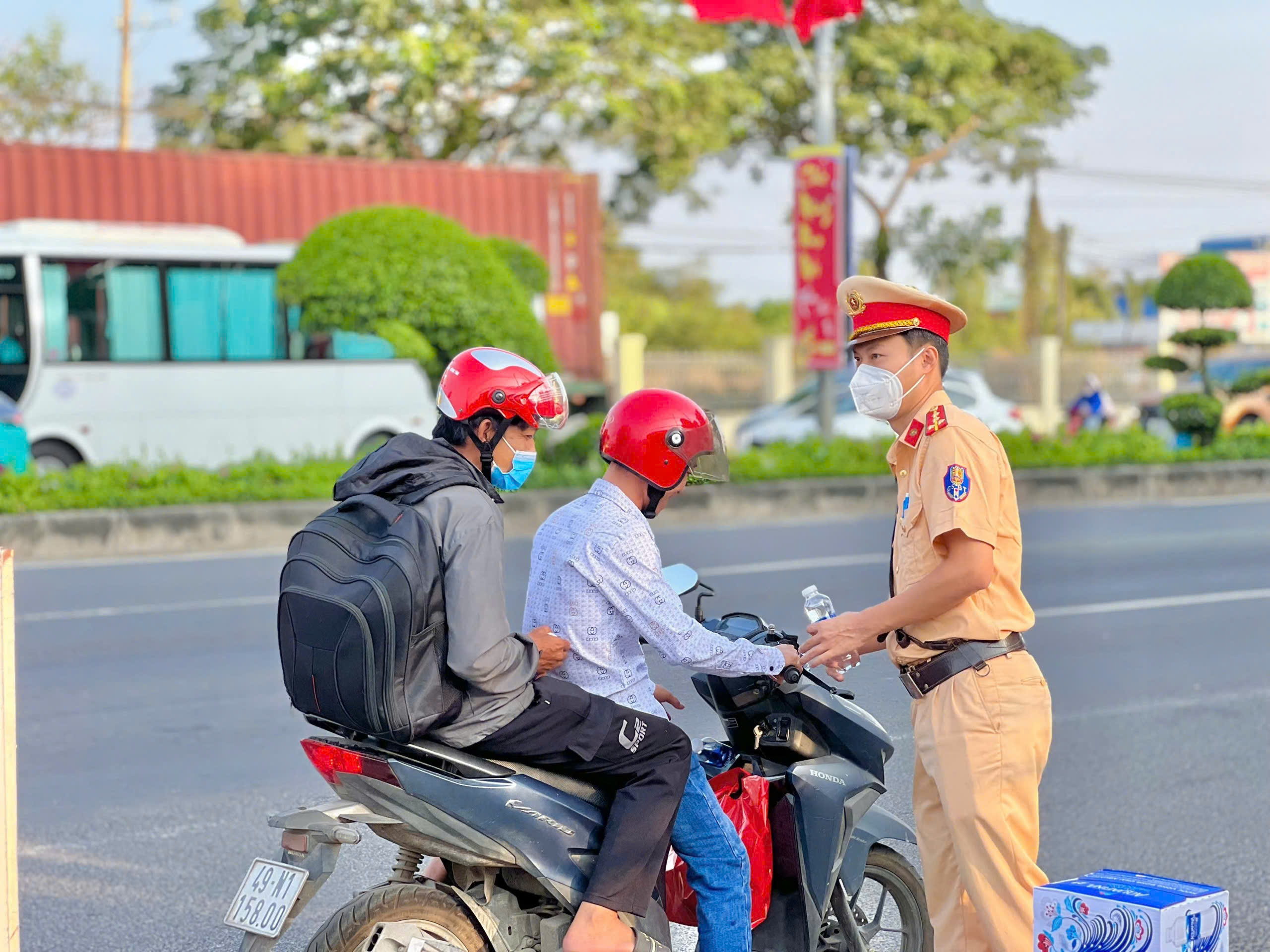 Cán bộ CSGT hỗ trợ nước uống cho người đi đường về quê đón Tết. 