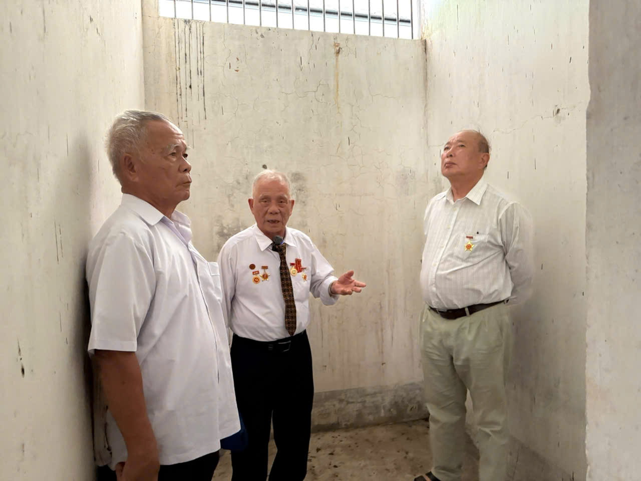 Cựu tù chính trị Ung Văn Khuê (bìa trái) thăm lại căn phòng giam tại Trại 7 Côn Đảo cùng các cựu tù.