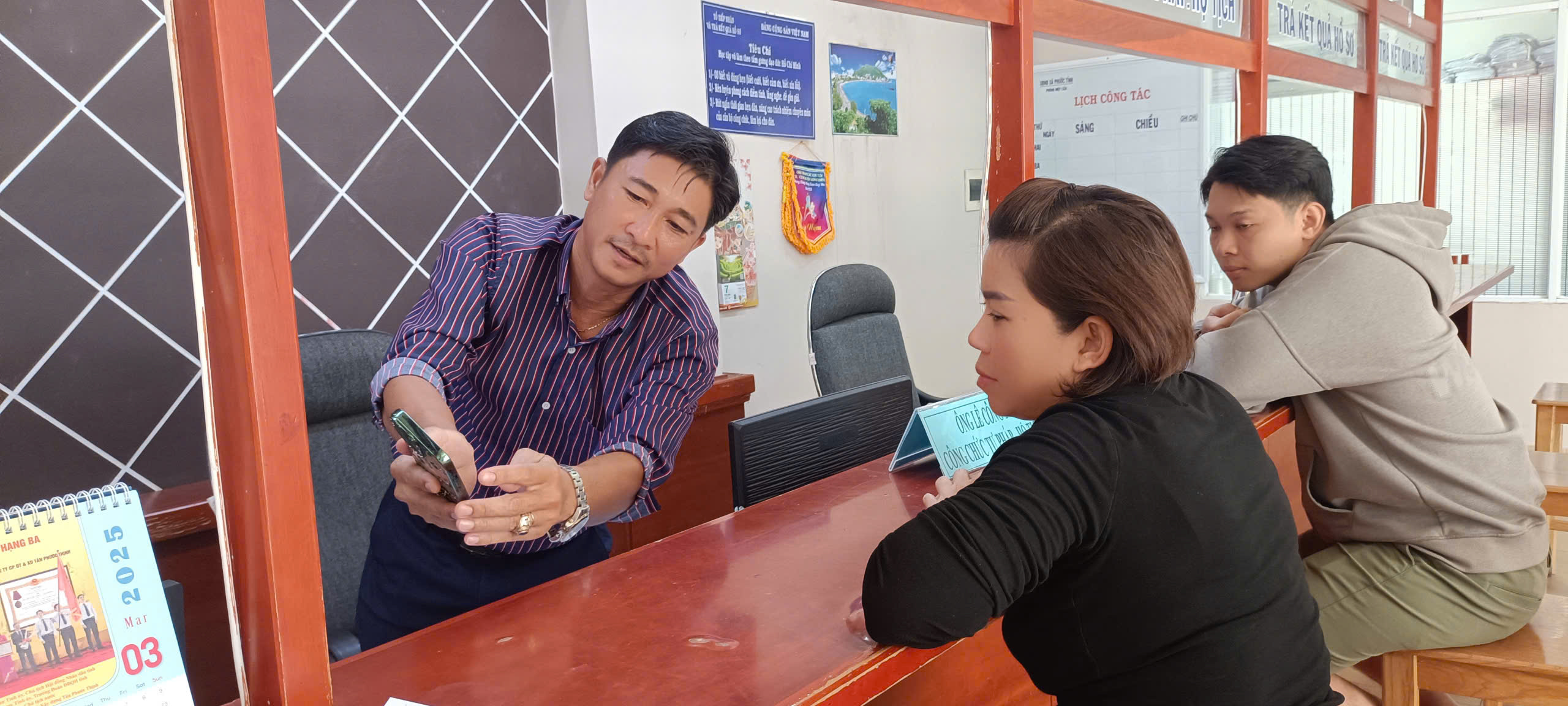 Cán bộ bộ phận một cửa UBND xã Phước Tỉnh (huyện Long Đất) hướng dẫn người dân sử dụng dịch vụ công điện tử trên App điện thoại.