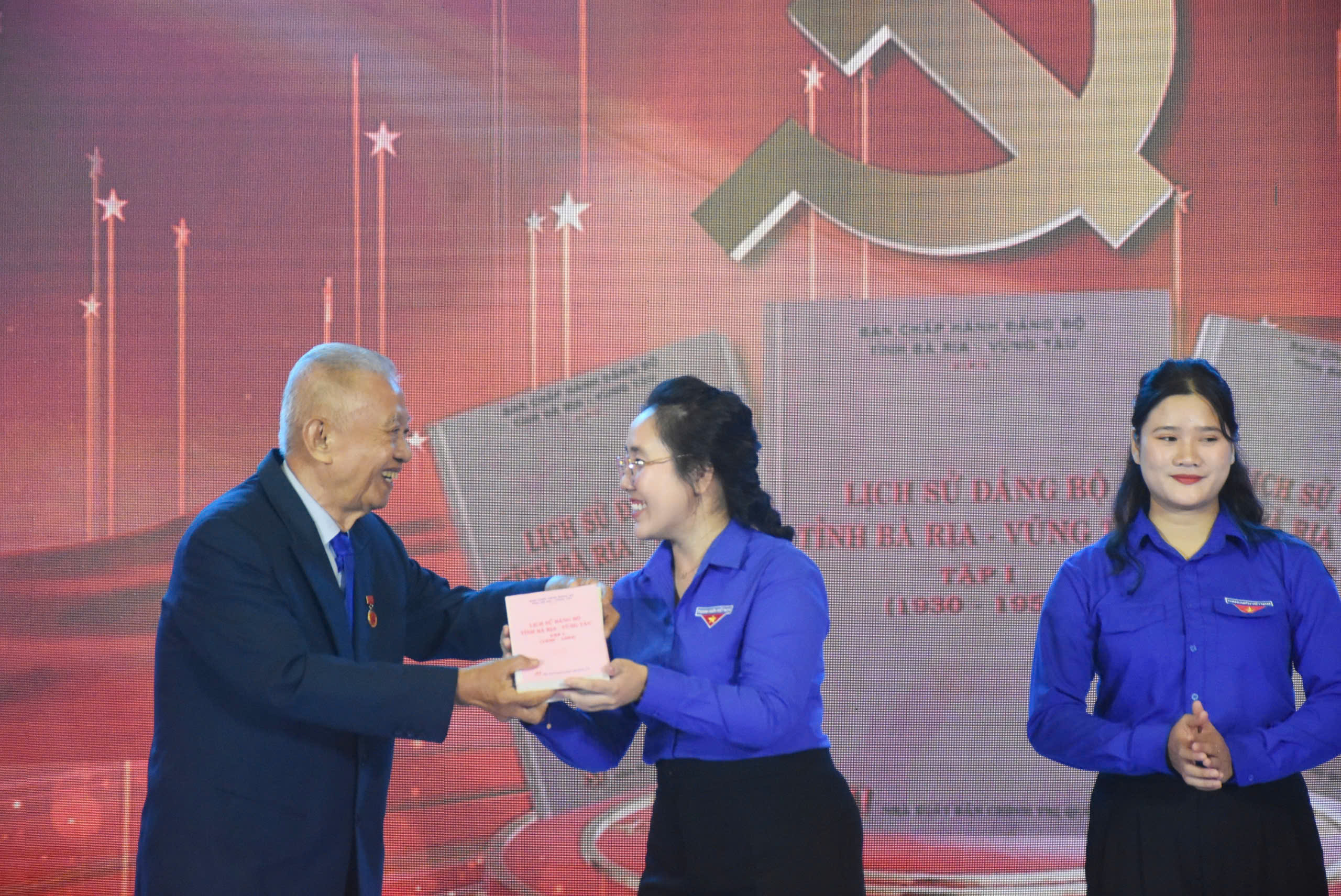 Ông Trần Văn Khánh, nguyên Bí thư Tỉnh ủy Bà Rịa-Vũng Tàu, đại diện cho thế hệ tham gia kháng chiến trao cuốn Lịch sử Đảng bộ tỉnh Bà Rịa-Vũng Tàu cho chị Nguyễn Thị Tuyết Kha, đại diện tuổi trẻ của tỉnh.