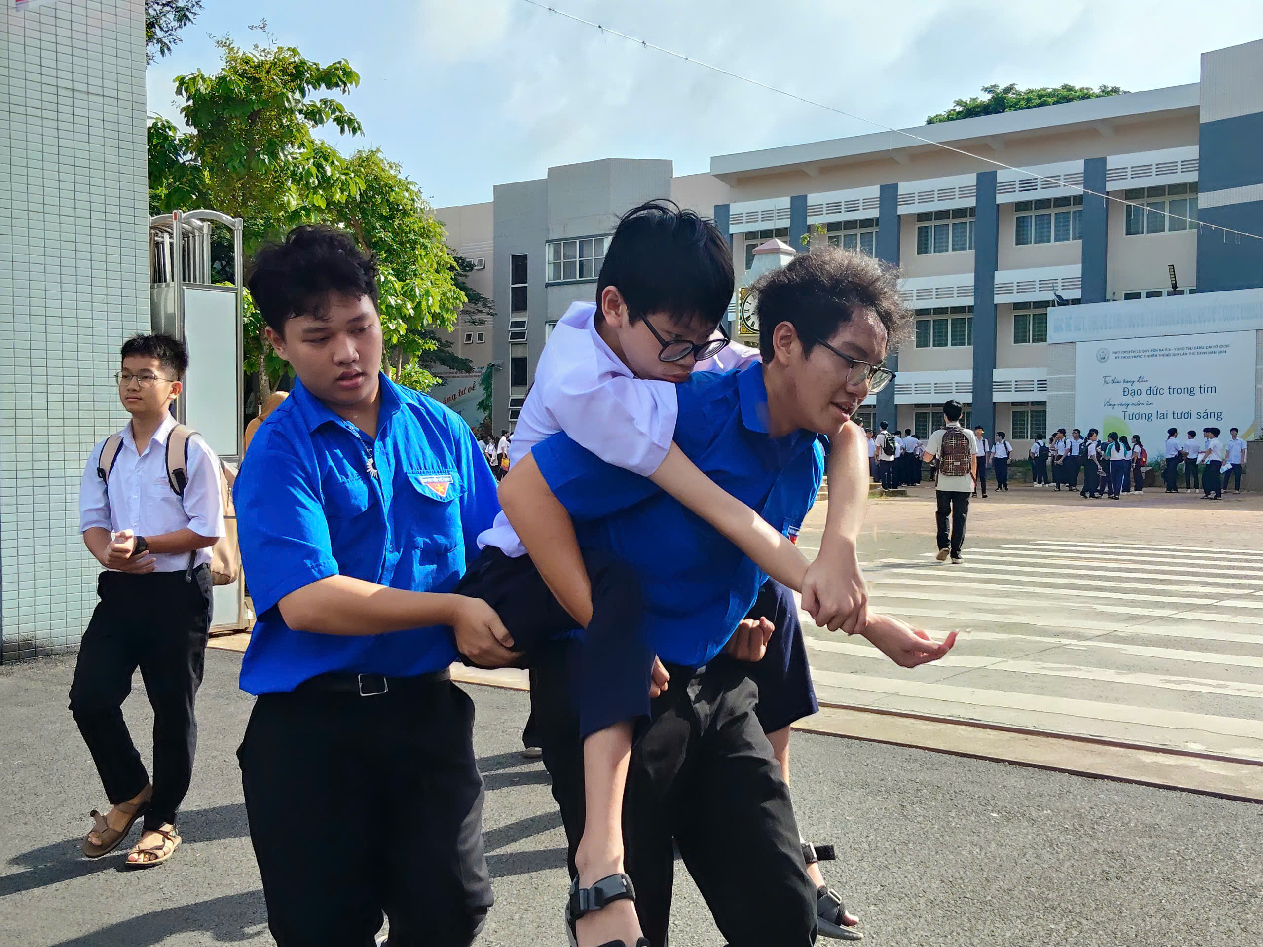 Thí sinh khuyết tật được tình nguyện viên tại điểm thi THPT chuyên Lê Quý Đôn đưa vào tận phòng thi.