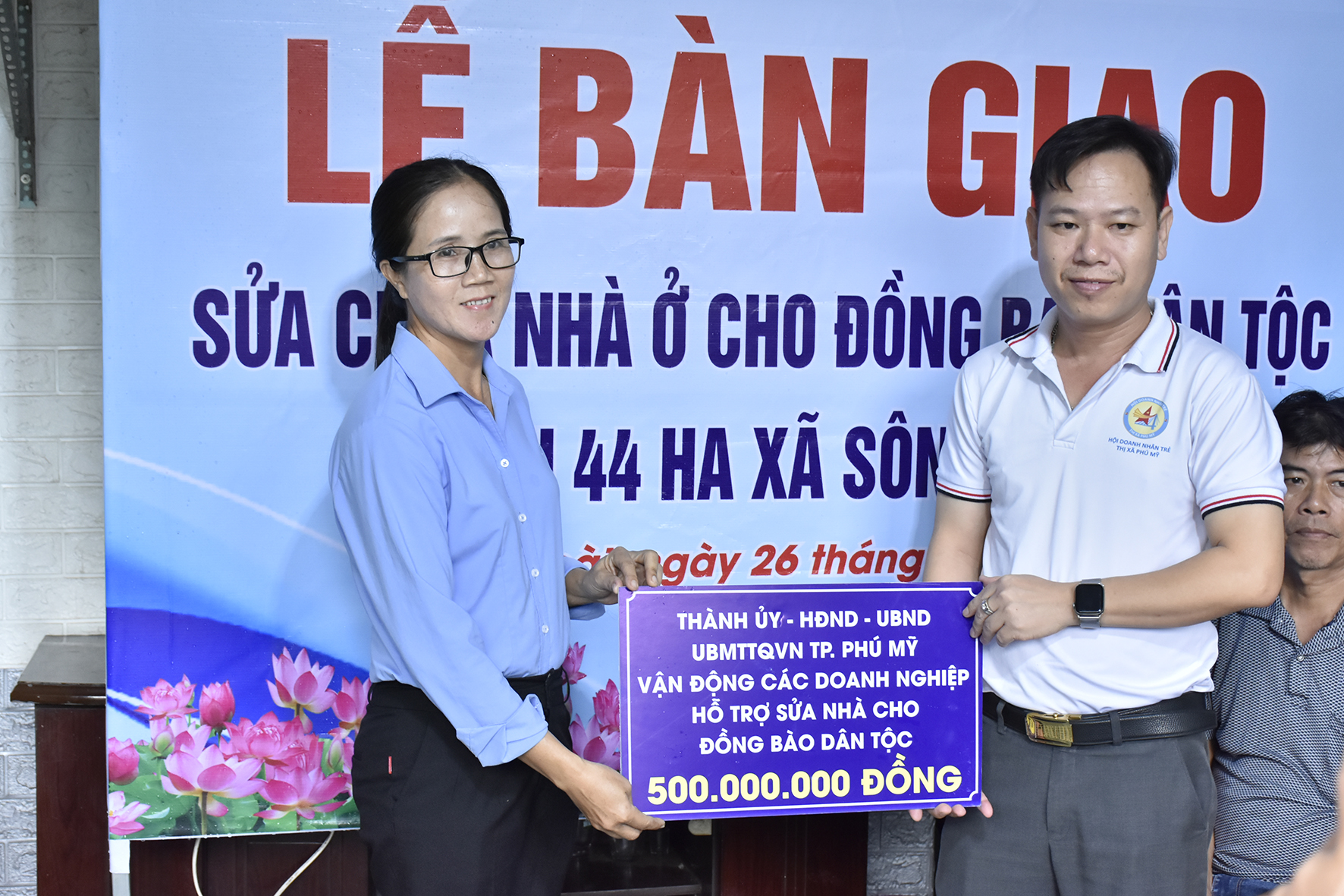 Đại diện Hội Doanh nhân trẻ TP.Phú Mỹ trao bảng tượng trưng ủng hộ kinh phí sửa chữa nhà cho đại diện địa phương. 