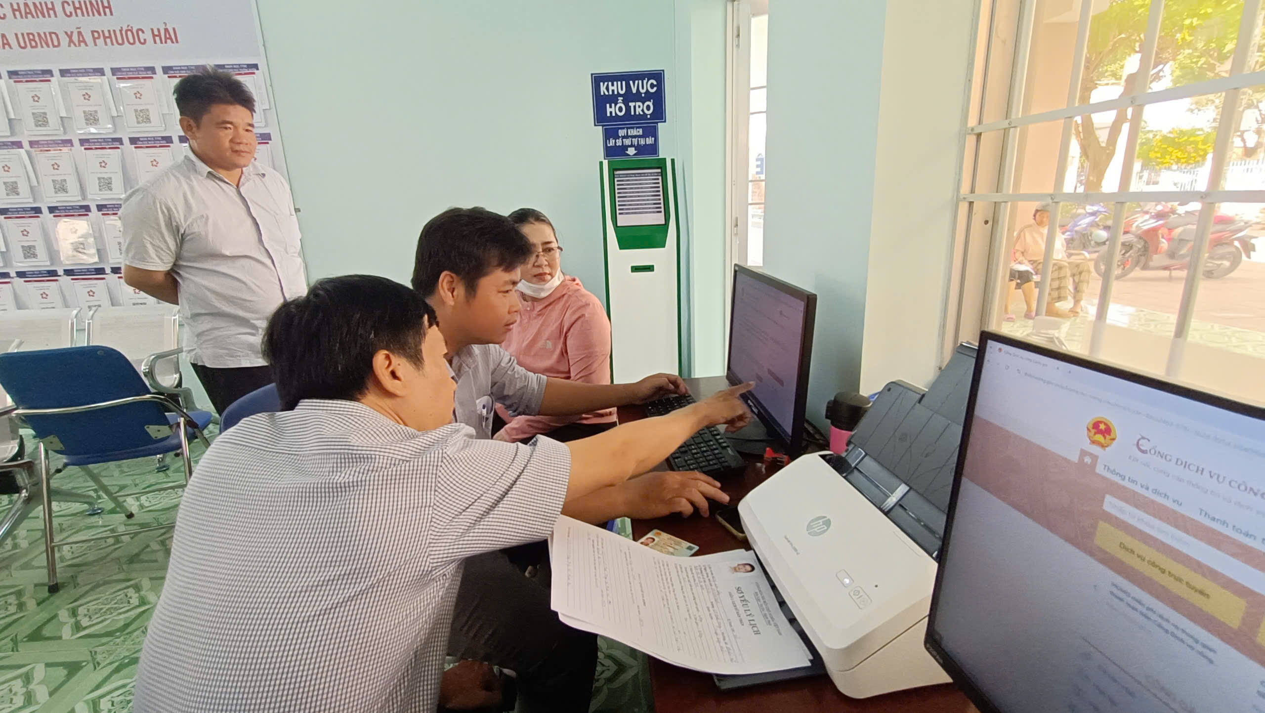 Cán bộ xã Phước Hải hướng dẫn người dân thực hiện thủ tục hành chính trực tuyến trên cổng Dịch vụ công. Ảnh: Ngọc Minh.
