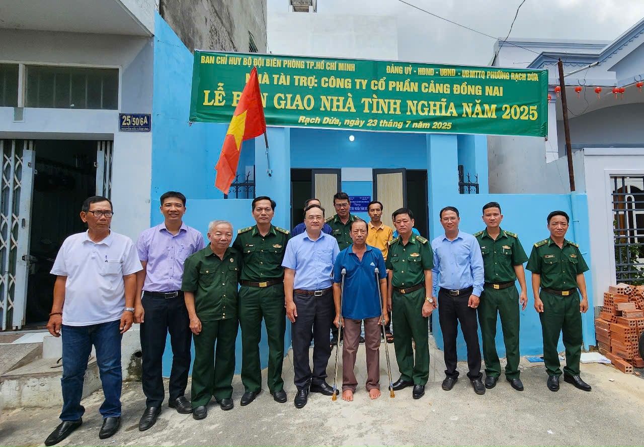 Đại biểu chụp hình lưu niệm trước căn Nhà tình nghĩa của ông Trần Văn Hùng.